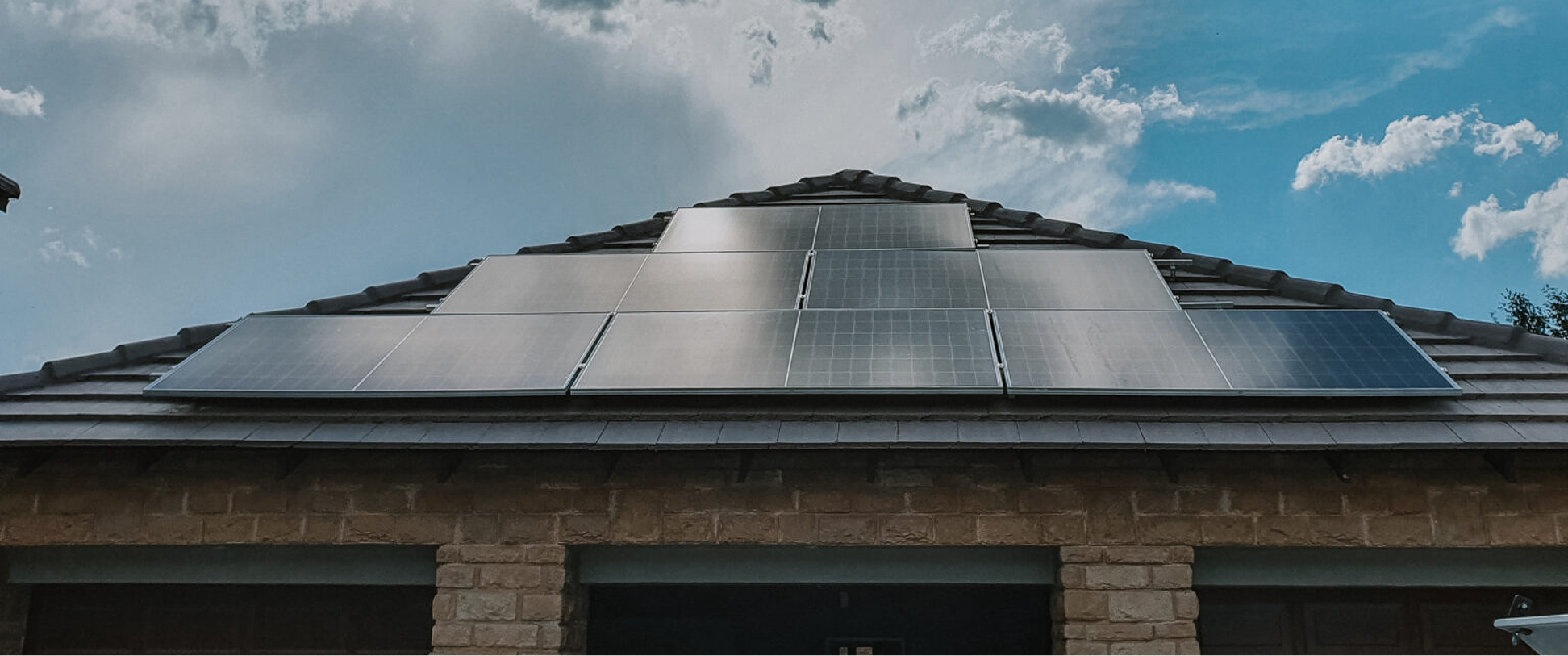 A modern residential solar panel array neatly installed on a concrete tiled roof above a double garage in a South African housing estate.